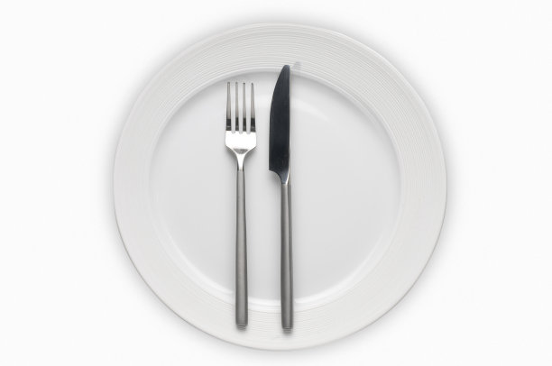 餐具放在一个盘子上——白色的瓷盘子和银色的刀叉图片下载