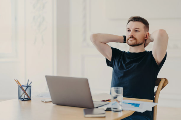 年轻的商人喜欢坐在办公室里用笔记本电脑完成工作图片下载