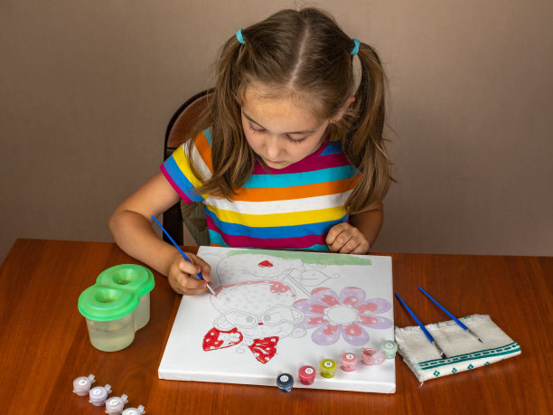 一个可爱的小女孩坐在桌边画画很开心。图片下载