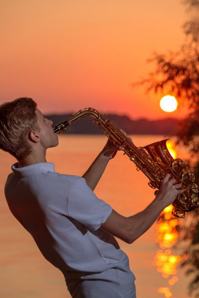 一个年轻人在傍晚日落时分吹萨克斯图片下载