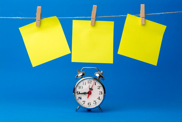 绳子旁边的时钟，上面挂着黄色的便签，上面写着目标、提醒、重要日期或生日。蓝色背景。是时候记住那些时刻了图片下载