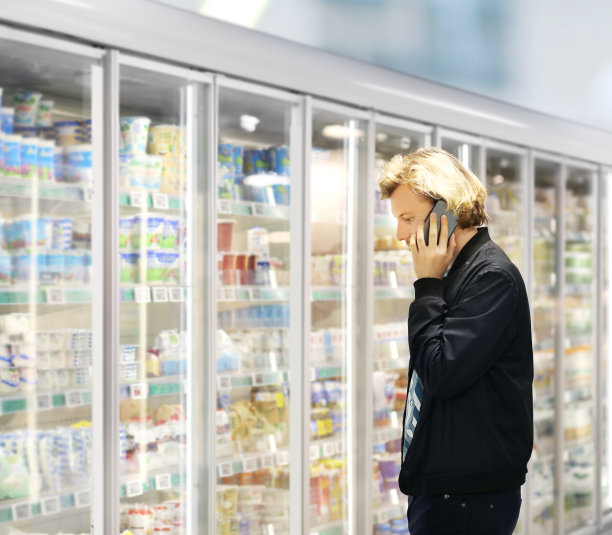 男人从超市冰柜选择冷冻食品并阅读产品信息图片下载