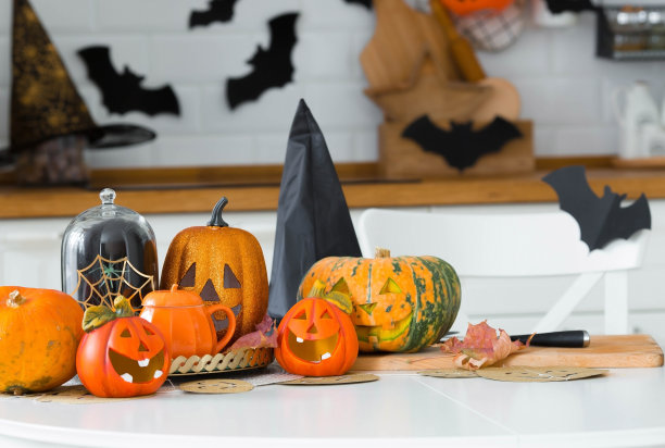 万圣节快乐!南瓜杰克在桌子上。灯笼雕刻着微笑和不同属性的节日在室内的灯光背景。全家在家里度假。Copyspace。图片下载