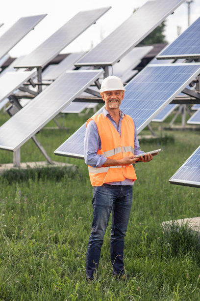 在镜头前，生态工程师带着安全设备和他的团队一起分析光伏太阳能电池板的工作效率，可再生能源的概念生态创新图片下载