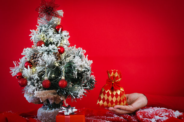 小装饰圣诞树和女献手礼。复制红色背景上的空间素材图片