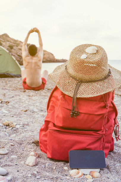 在大海前的海滩营地里做瑜伽的一个不知名的男人的垂直图像。健康的生活方式理念和运动的本质。图片下载