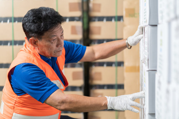 在产品仓库工作的亚洲男性工人。男工人检查货架托盘包裹的产品。检验、质量控制图片下载