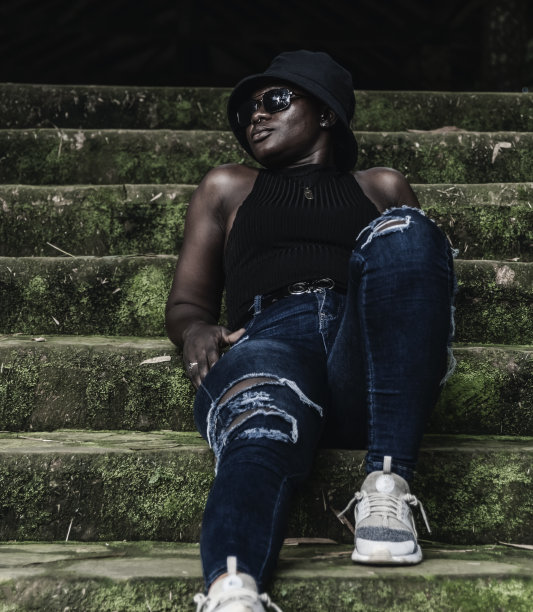 非洲年轻女子戴着帽子坐在旧楼梯上图片下载