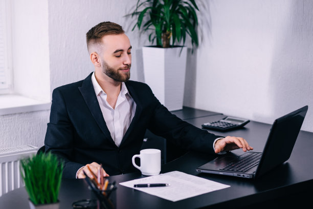 年轻的商人在家里用笔记本电脑和纸工作图片下载