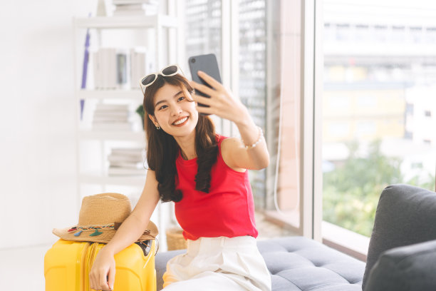 东南亚年轻成年女子旅行前用智能手机自拍的肖像图片下载