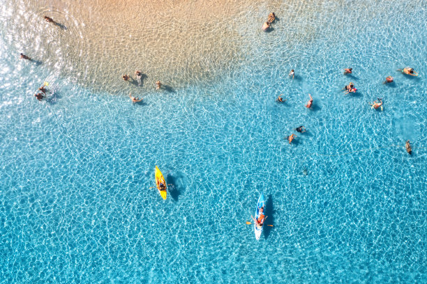 鸟瞰皮划艇，人们在蓝色的大海和日落时的沙滩上游泳。意大利撒丁岛的夏天。从无人机俯视独木舟，海岸，透明的水。色彩斑斓的热带景观。旅行图片下载