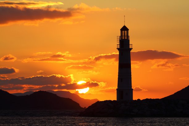 在阳光海景。灯塔和海岸上的航船。海边小镇Turgutreis，阳光灿烂图片下载