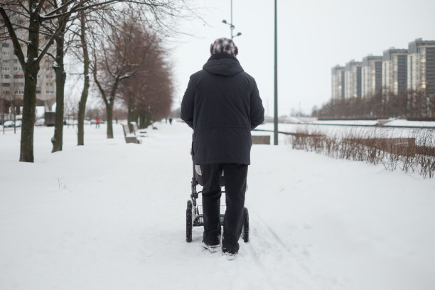 祖父在下雪的冬日里推着婴儿车散步图片下载