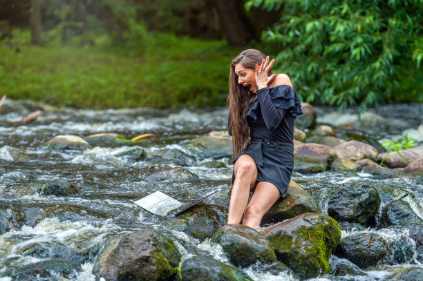 女自由职业者坐在河里的一块石头上把她的笔记本电脑扔进水里图片下载