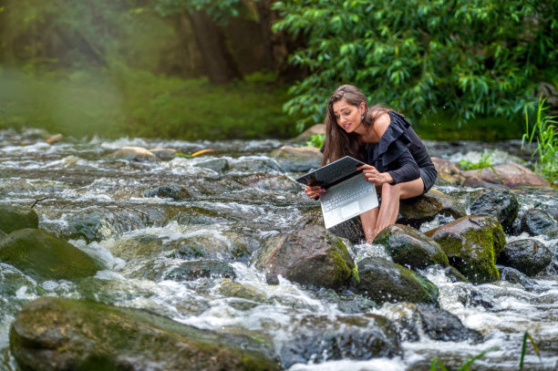 忧心忡忡的女子从水中拔出笔记本电脑，称其掉进河里，远程假期工作意外图片下载