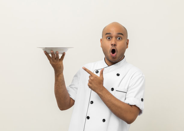 哇兴奋的菜单。年轻英俊的亚洲男子厨师在制服拿着空盘子美味的菜菜单好味道上孤立。印度人的职业厨师，厨房、餐厅和酒店的人。图片下载