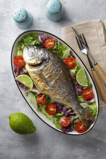 烤整个多拉多鱼盘子上的新鲜蔬菜上浅灰色的背景俯视图垂直照片图片下载