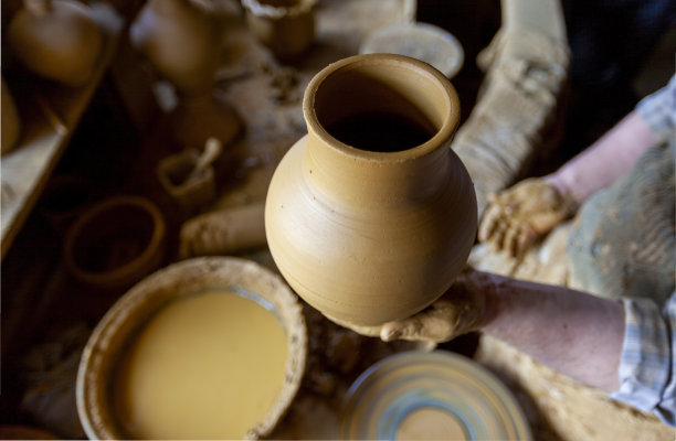 妇女在陶工的转盘上工作。手用陶罐雕刻出一个杯子。陶工转盘上的模型工作坊。图片下载