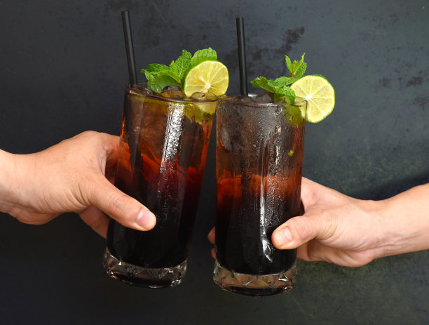 双手在黑色的背景上用桑葚酒鸡尾酒碰杯图片下载