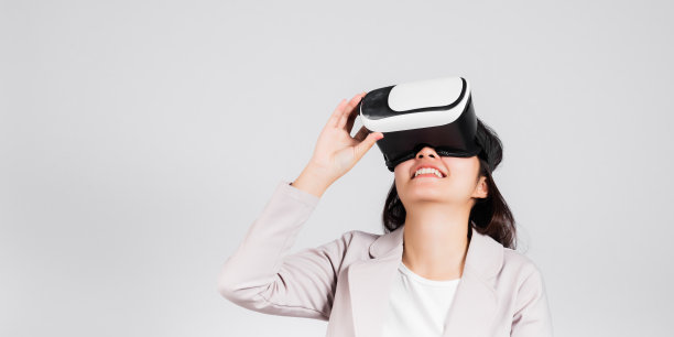 微笑的女人自信兴奋地戴上VR头戴设备进行虚拟现实体验图片下载