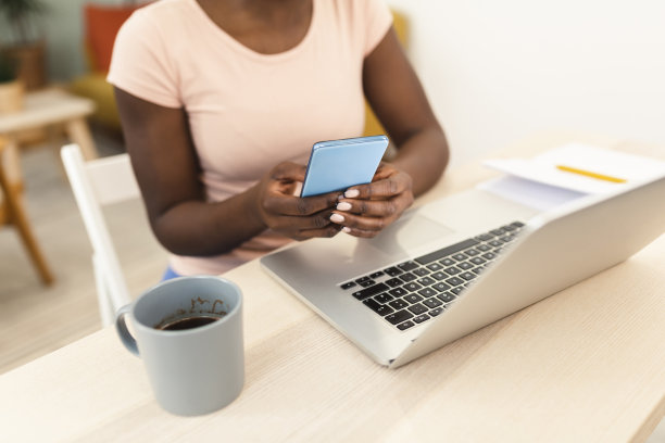 不知名的非洲裔美国女性在上网工作时使用智能手机图片下载