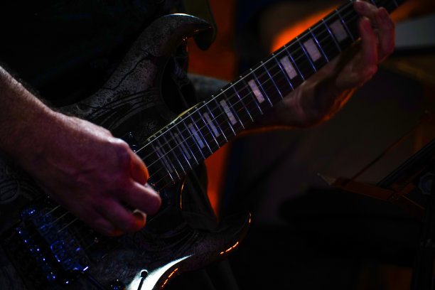 吉他手在一间黑屋子里弹吉他。弹吉他的吉他手的手。低调图片下载