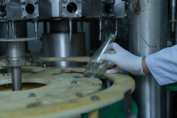 果汁生产线的产品质量控制官对用来装果汁的瓶子进行检查图片下载