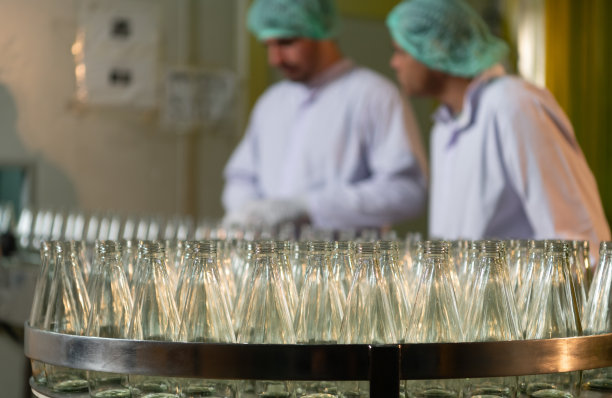 果汁生产线的产品质量控制官对用来装果汁的瓶子进行检查图片下载