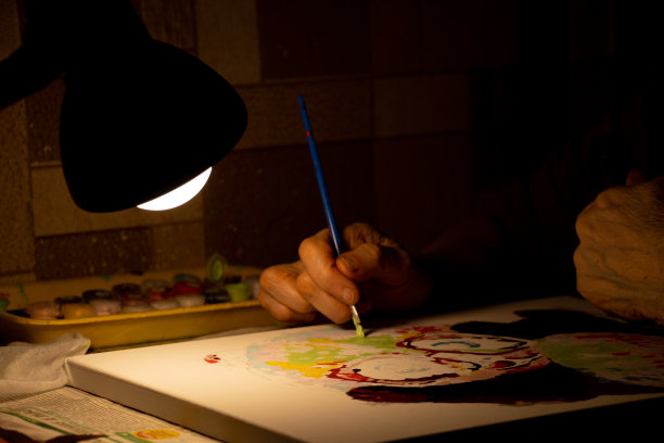 老妇人在黑暗中用油彩在画布上画一幅画，在家里画一幅画，艺术和爱好，奶奶的图片下载