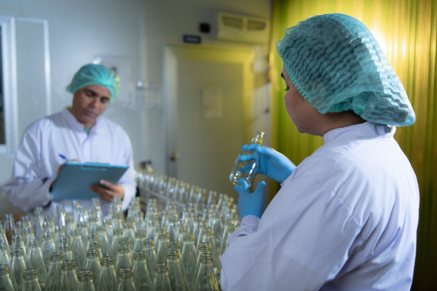 果汁生产线的产品质量控制官对用来装果汁的瓶子进行检查图片下载