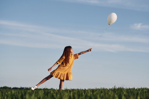 玩气球。快乐的女孩在夏天在户外的田野上散步图片下载