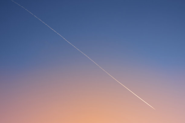 日落后，白色对角线飞机在清晰的梯度夜空上的轨迹。飞机跟踪。图片下载
