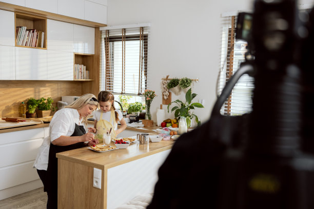 奶奶和孙子一边录制烹饪节目，一边在厨房烘焙饼干。在电视节目中拍摄关于烘焙饼干的视频图片下载