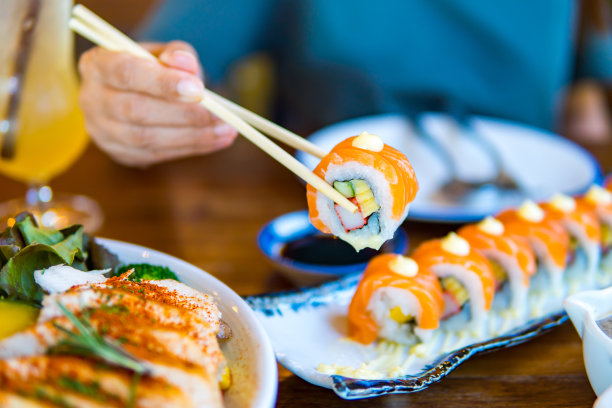 日本餐厅的餐桌上，人们用筷子夹着寿司。图片下载