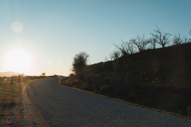 日光下弯曲的道路背景。图片下载