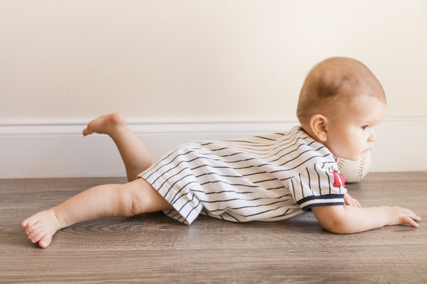 7个月大的小男孩穿着棒球服，在家里的木地板上玩垒球图片下载