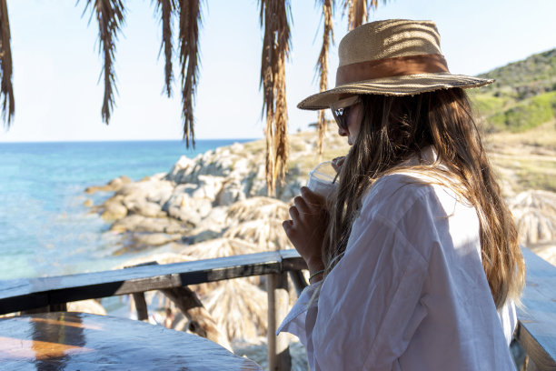 快乐的女人享受在海滩咖啡馆放松快乐的热带蓝色的水。图片下载