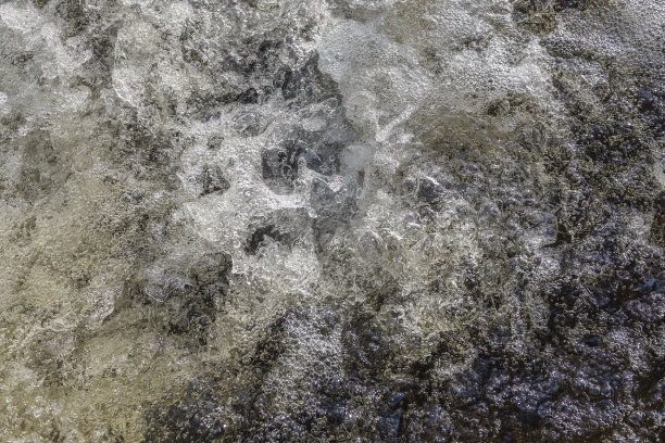 在瀑布旁，水在湍急的水流中冒泡溅起水花。图片下载