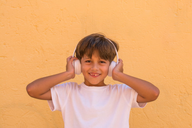 小学年龄微笑的男孩听音乐与无线耳机。图片下载