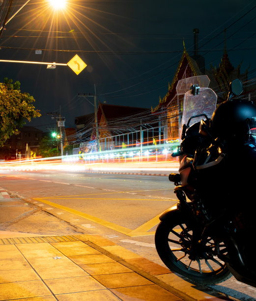 晚上把摩托车停在路边，摩托车前面的剪影，背景是用长曝光技术拍摄的。图片下载