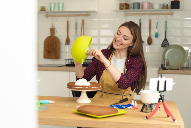 一个快乐的女人正在做蛋糕，并为她的社交媒体拍摄照片图片下载