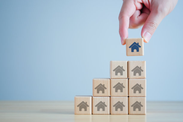 房地产。房屋及物业投资及资产管理概念。利率，贷款抵押，房产税。手从众多的房子中挑选蓝色的房子。选择最好的物业。图片下载