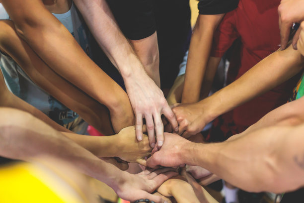 孩子们篮球队的孩子们在球场上叠手，运动队的队员们一起手拉着手准备比赛，打室内篮球，球队与教练交谈，近距离的手图片下载