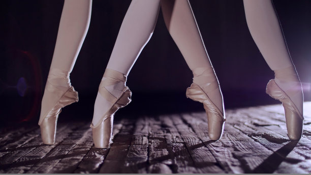 在聚光灯下，老剧院舞台的特写。芭蕾舞者穿着尖头鞋，踮起脚尖，优雅地表演一定的芭蕾舞动作，在第二姿势上下移动图片下载