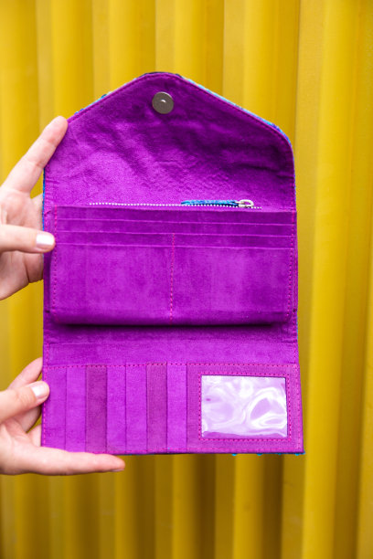 闭上时髦的紫色钱包由妇女手中拿在明亮的黄色背景，打开空产品，图片下载
