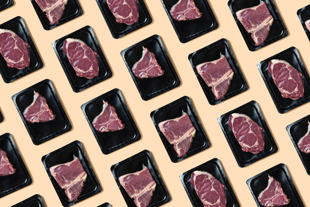 真空包装的生鲜肉。米色背景的t骨牛排图片下载
