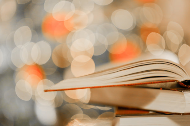 关于圣诞节和冬天主题的书。堆叠的书在桌子上闪光闪烁的花环的背景。冬天的书。圣诞故事，故事，神话和传说。图片下载