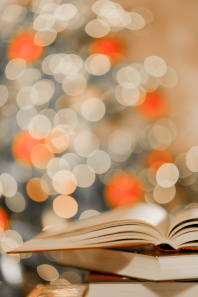 关于圣诞节和冬天主题的书。堆叠的书在桌子上闪光闪烁的花环的背景。冬天的书。图片下载