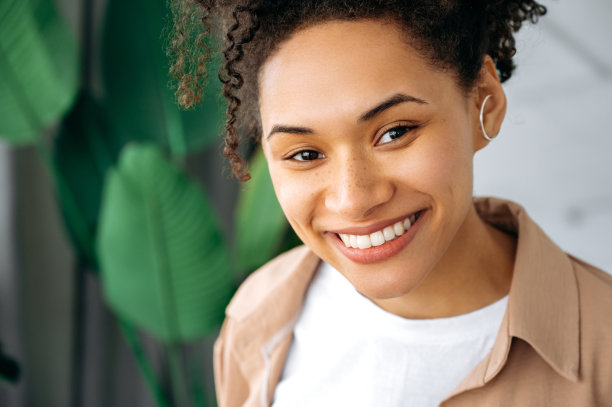 特写照片积极华丽的非洲裔美国卷发女孩，混血女性雀斑和完美的白色修剪的牙齿，看着相机，快乐的牙齿微笑图片下载