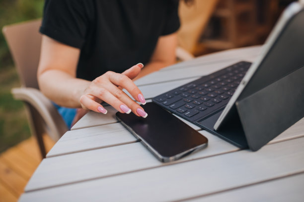 在一个阳光明媚的日子里，一个自由职业者在舒适的野营帐篷里打电话和使用笔记本电脑的特写。豪华野营帐篷，适合暑假和度假户外使用。生活方式的概念图片下载